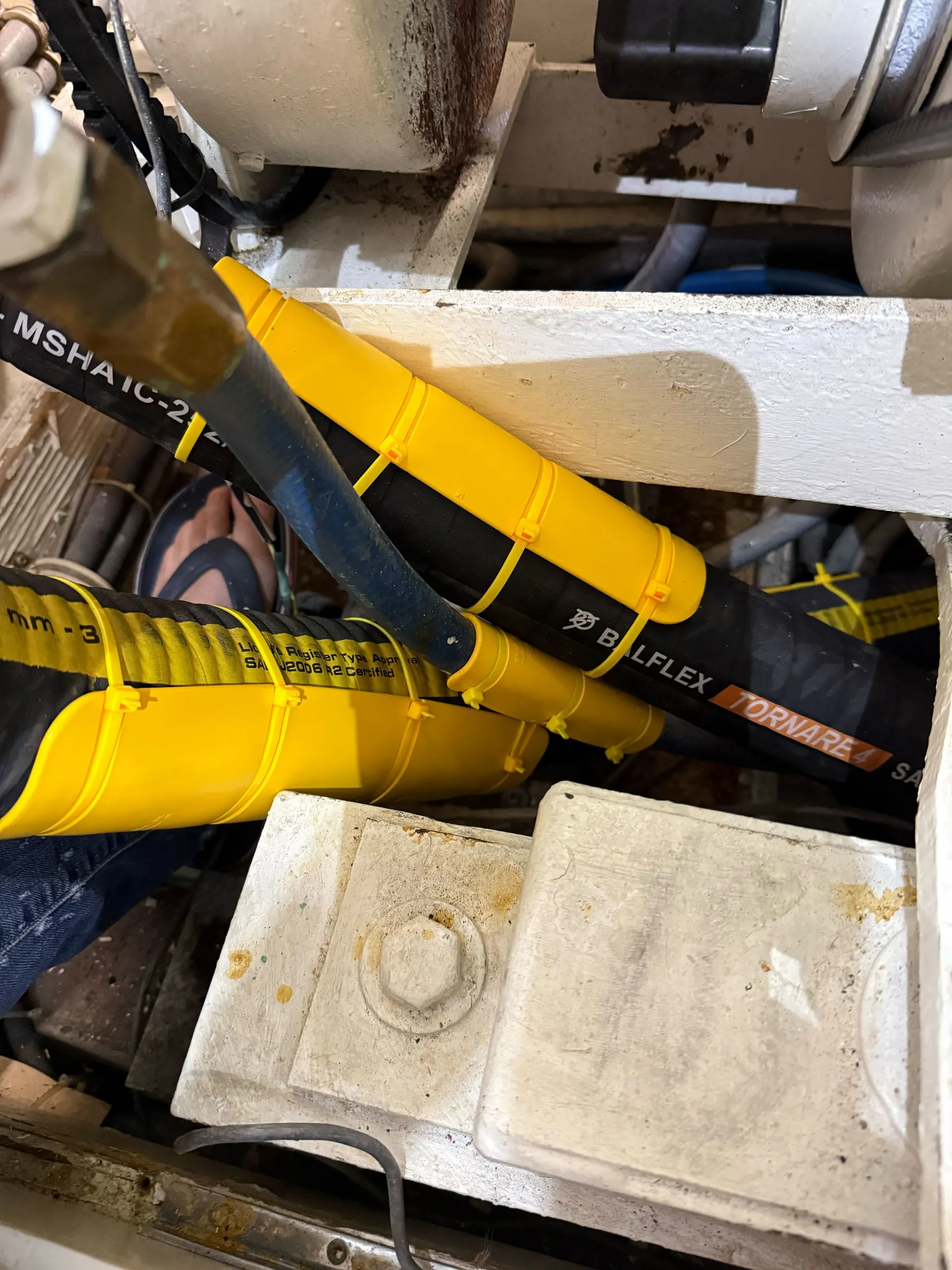 Yellow EPHA protector on a Balflex Tornare4 SAE hydraulic hose at a bend point near the engine