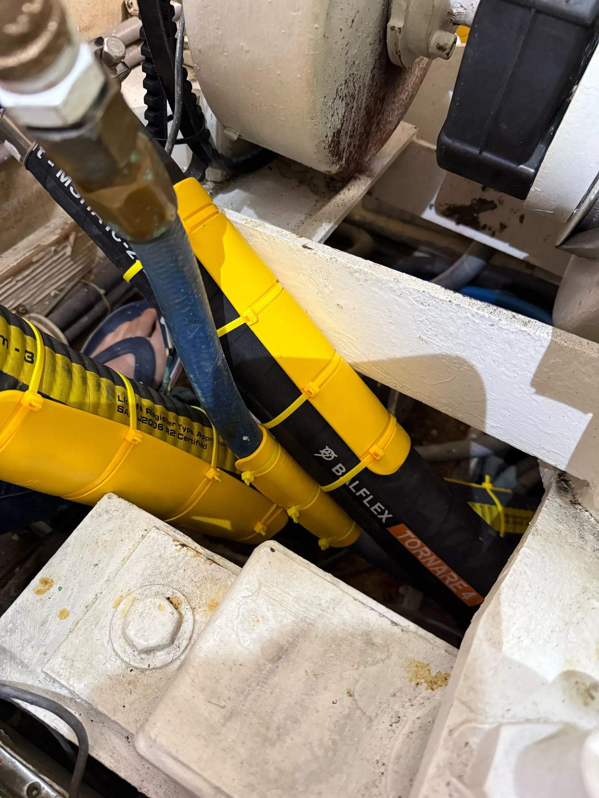 Multiple hydraulic hoses running alongside a Caterpillar engine in a marine engine bay