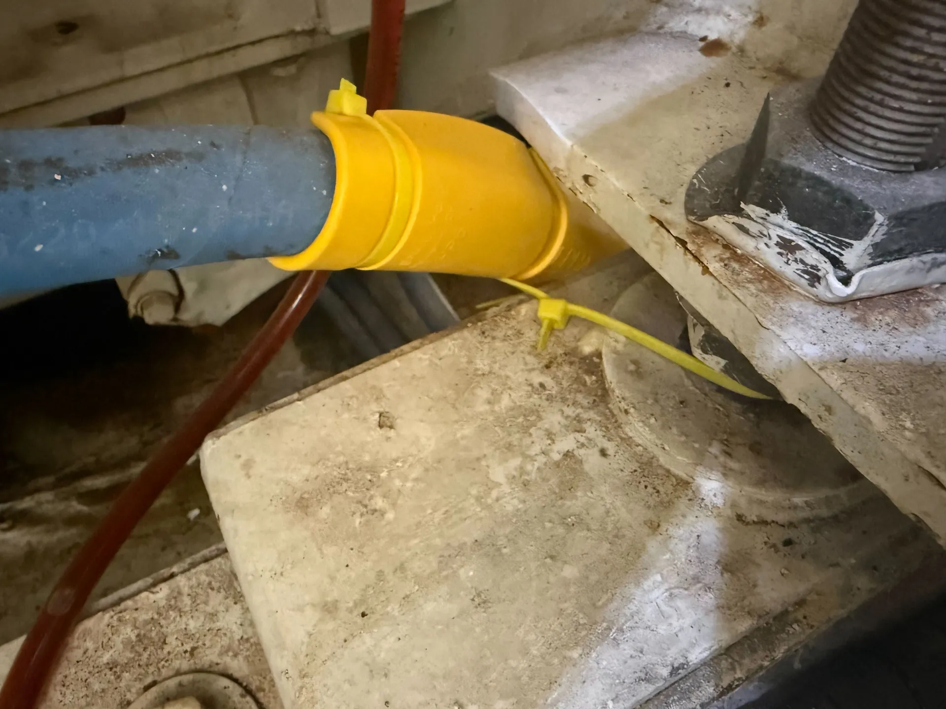 Yellow EPHA protector secured with yellow cable ties on a hydraulic hose at a metal edge