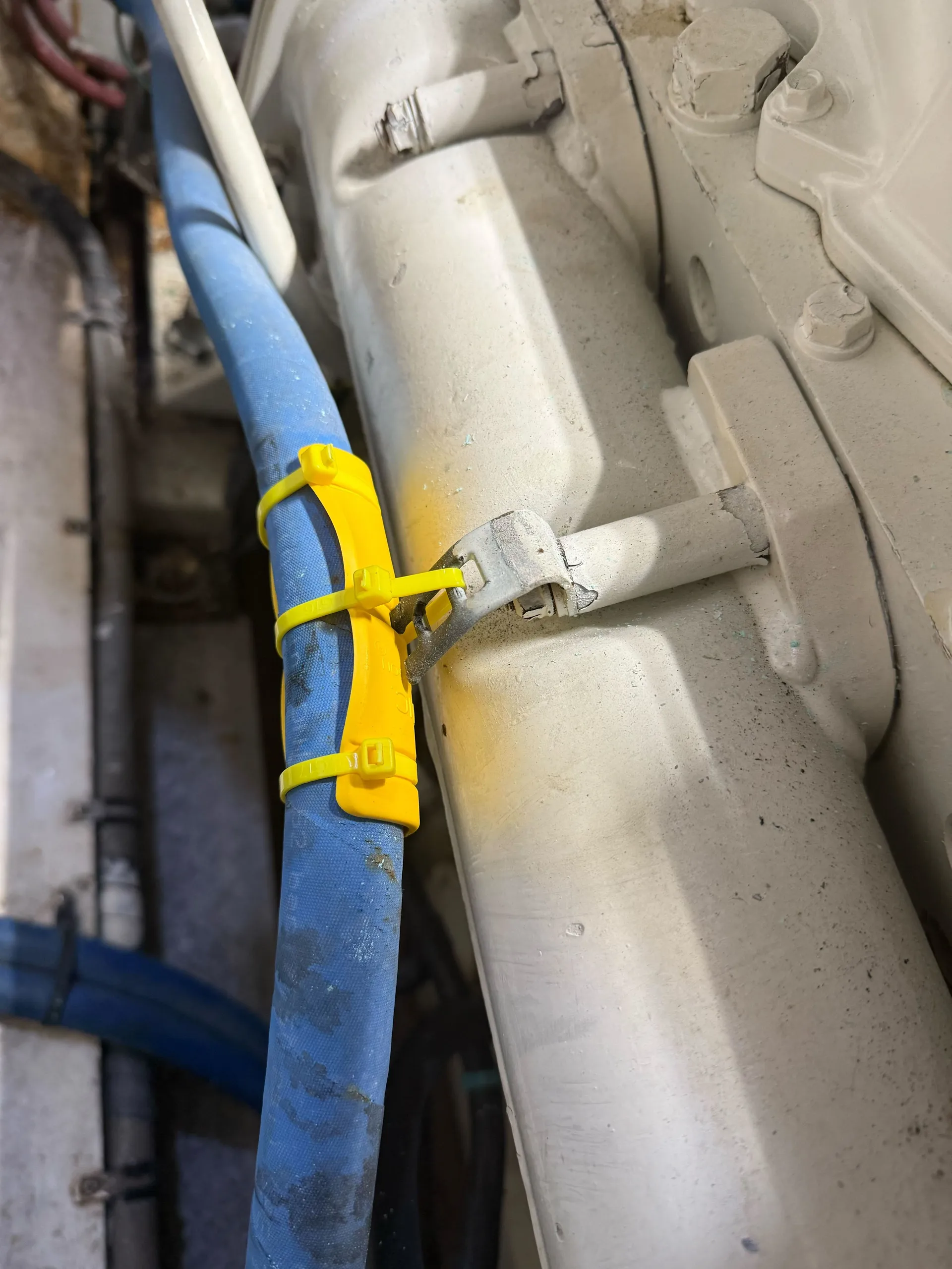 Yellow EPHA hose protector on a hydraulic hose where it contacts a metal bulkhead