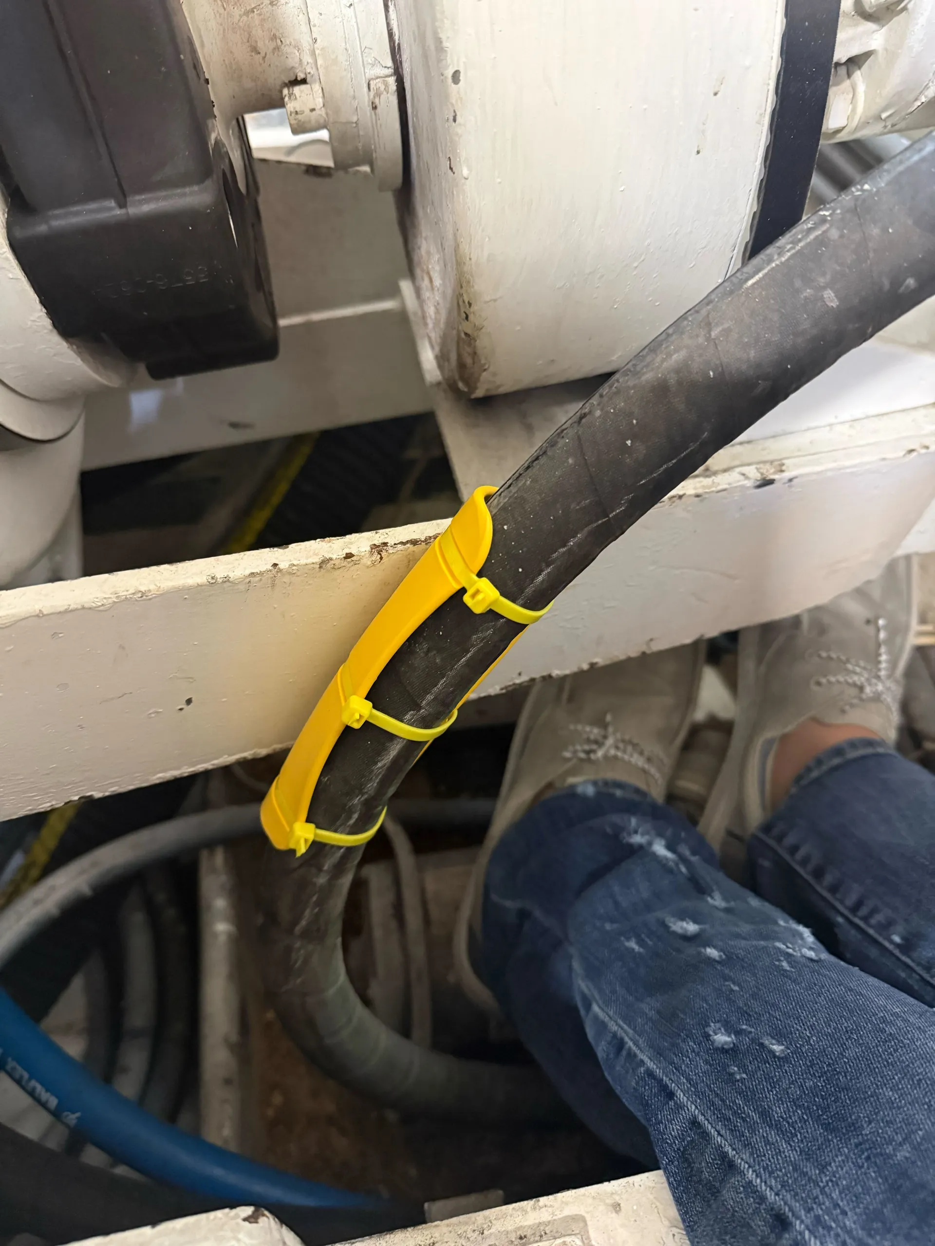 Yellow EPHA hose protector installed on a hose resting against a metal frame member